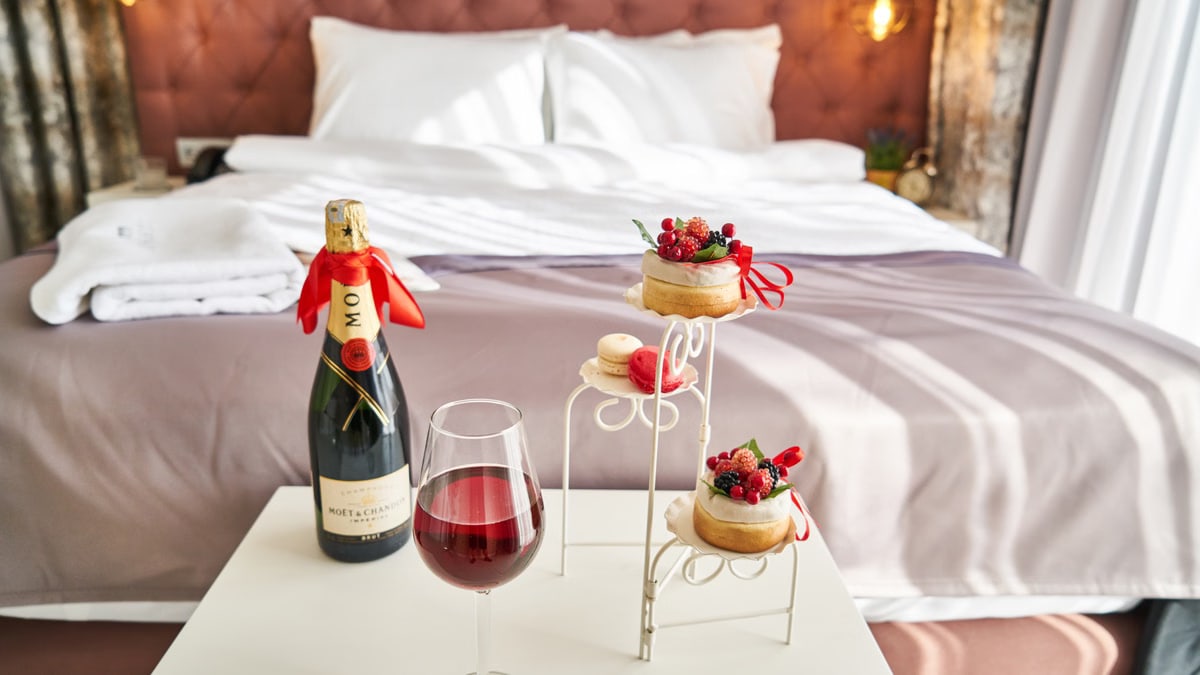 Elegant bedroom setting with champagne, wine glass, and desserts, creating a cozy ambiance.